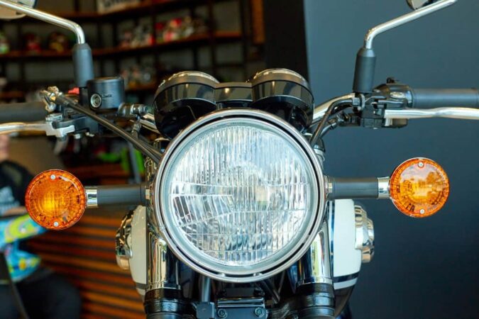 Gros plan sur le phare rond chromé et les clignotants oranges d'une moto classique