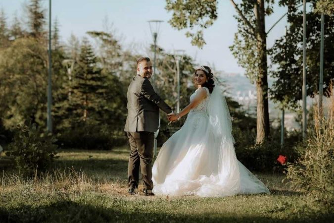 Mariés se tenant la main dans un parc verdoyant au coucher du soleil, illustration d'un mariage réussi en sachant gérer son budget mariage.