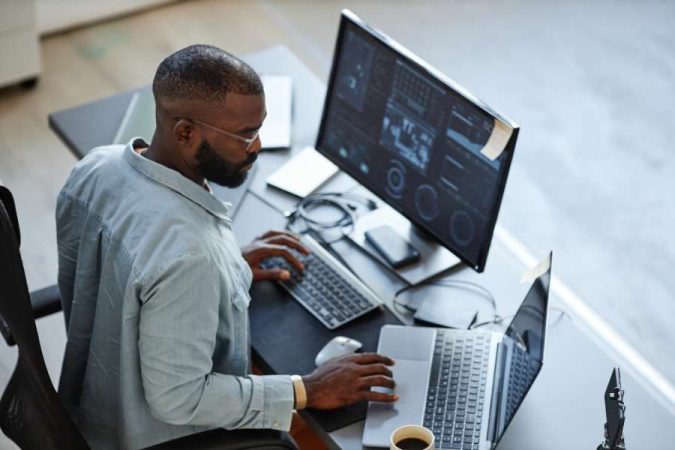 Homme travaillant sur un ordinateur avec un logiciel de détourage d'image automatique.