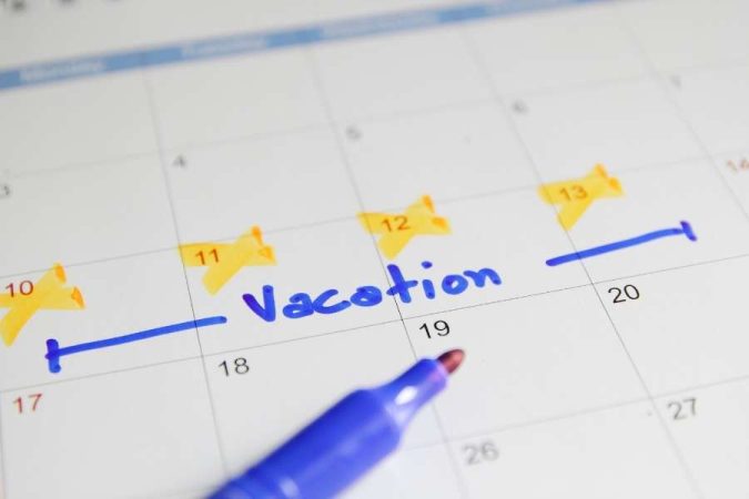 Un calendrier mural coché avec le mot vacances écrit au feutre bleu.