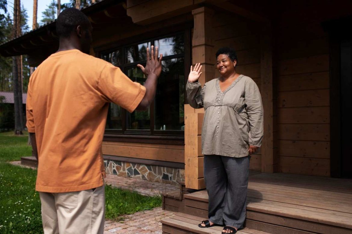 Un homme et une femme se saluent chaleureusement de la main devant une maison pour comprendre comment se faire des amis quand on arrive dans une nouvelle ville.